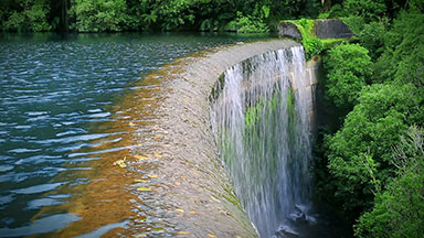 Waterfall over an old dam surrounded by forest