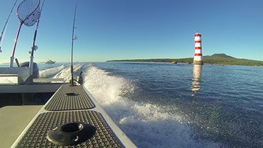 Motor boat fish-eye view passing lighthouse