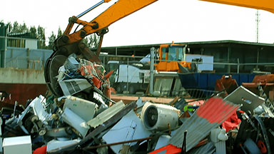 Excavator loads scrap metal junk into bin